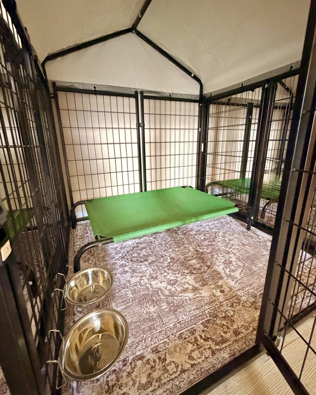 Inside a 4 by 4 Bark Inn suite: a raised cot, rug and bowls